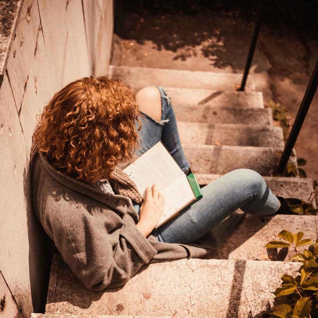 Teeny sitzt auf der Treppe am Schulhof